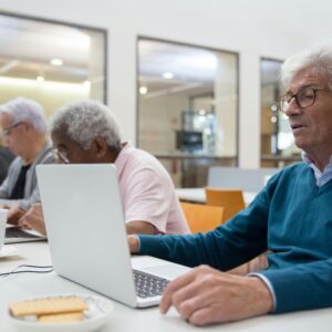 Seniors learning computer skills in a classroom setting, enhancing technology understanding.