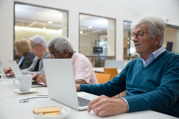 Seniors learning computer skills in a classroom setting, enhancing technology understanding.